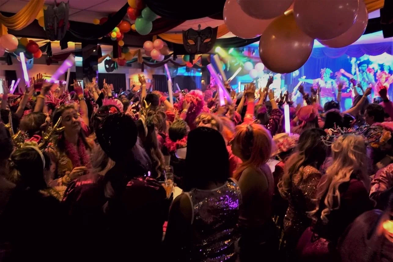 Carnavalssfeer met een volle feestzaal en lichtstaven